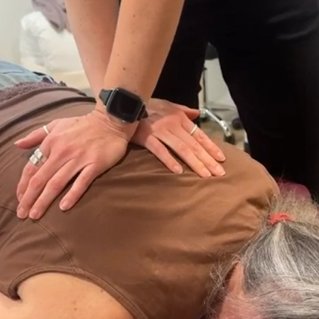 Chiropractic adjustment being performed with precise hand placement on the mid‑back.