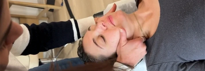 A patient lying on a table receives a chiropractic adjustment in the neck.