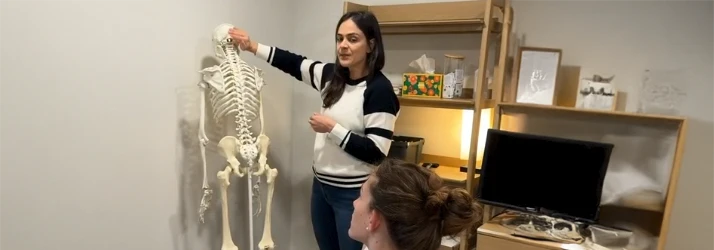 Dr. Ali Perez explains skeletal alignment using an anatomical model during consultation.
